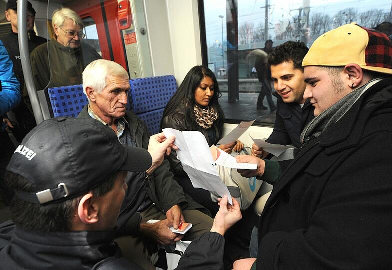 &bdquo;Kennen Sie die?&ldquo;: Ein Bundespolizist hält S-Bahn-Fahrgästen Fotos von mutmaßlichen Vandalen hin.