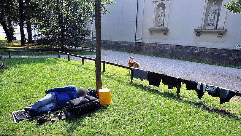 Ein Mann schläft neben seinem Koffer in der Wiese neben der Glyptothek. An der Umzäunung hängt seine Wäsche zum Trocknen. Ein Mann schläft neben seinem Koffer in der Wiese neben der Glyptothek. An der Umzäunung hängt seine Wäsche zum Trocknen.