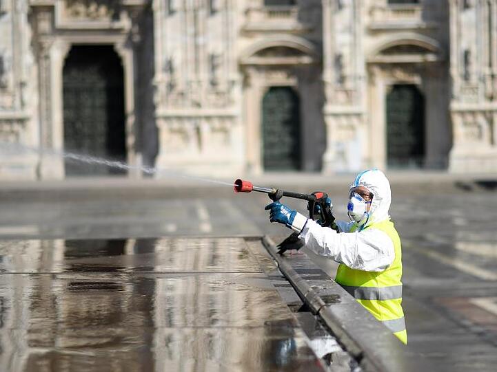 Ein Arbeiter in Schutzanzug reinigt den Piazza del Duomo in Mailand.