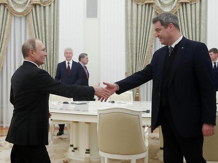 Wladimir Putin und Markus Söder geben sich die Hand. Foto: Maxim Shemetov/Pool Reuters/AP/dpa