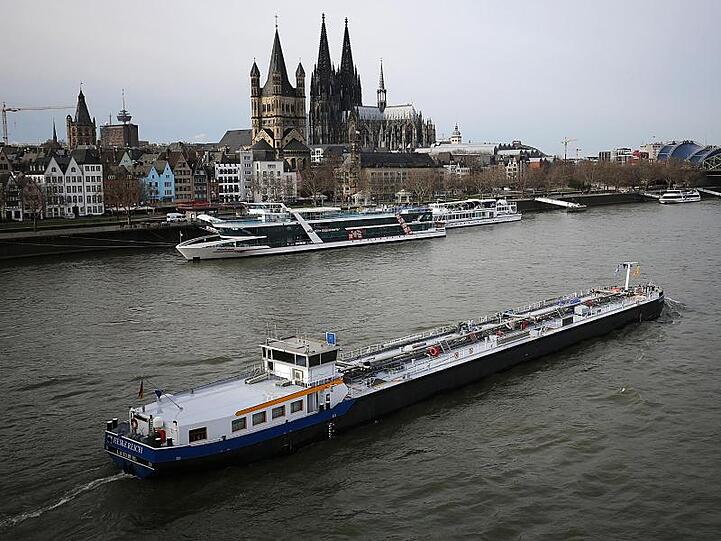 Ein Binnenschiff fährt vor dem Dom über den Rhein.