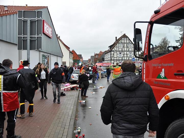 Polizisten, Feuerwehrleute und Passanten stehen an der Stelle, an der das Auto in eine Menschenmenge gefahren war.