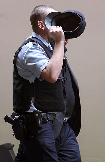 Ein Polizist geleitet eine Angehörige vorbei an den Pressevertretern.