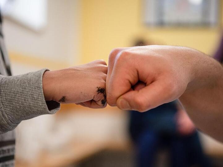 Ein Insasse gibt in der Vater-Kind-Gruppe in der JVA Nürnberg seinem Sohn einen Fist Bump.
