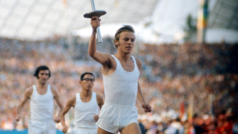 So hat die Er&ouml;ffnung der Olympischen Sommerspiele 1972 in M&uuml;nchen ausgesehen:  Der deutsche Mittelstreckenl&auml;ufer G&uuml;nther Zahn l&auml;uft mit der Olympischen Fackel ins M&uuml;nchner Olympiastadion ein, gefolgt von weiteren Staffell&auml;ufern.