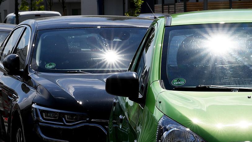 Sonne scheint auf parkende Autos.