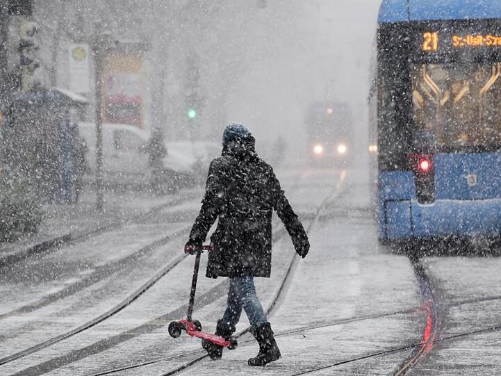 Ein Passantin läuft in den Morgenstunden bei dichtem Schneetreiben durch München.
