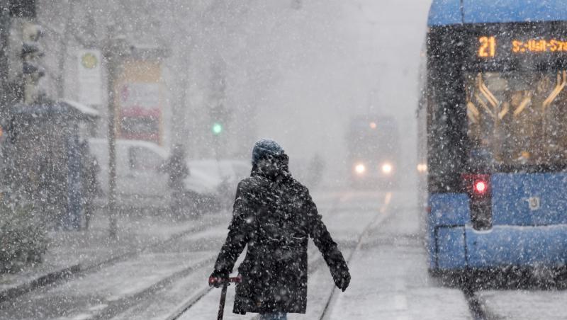 Ein Passantin läuft in den Morgenstunden bei dichtem Schneetreiben durch München. Ein Passantin läuft in den Morgenstunden bei dichtem Schneetreiben durch München.