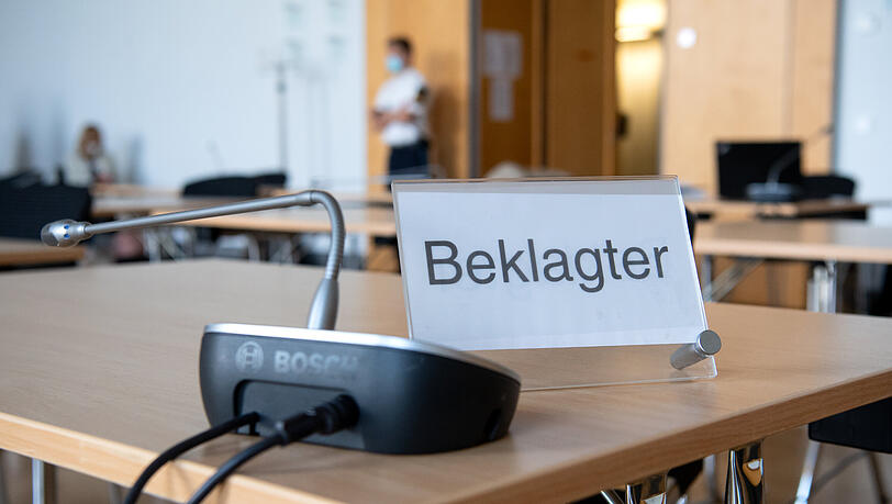 Ein Schild mit der Aufschrift "Beklagter" steht vor Verhandlungsbeginn in einem Gerichtssaal im Landgericht.