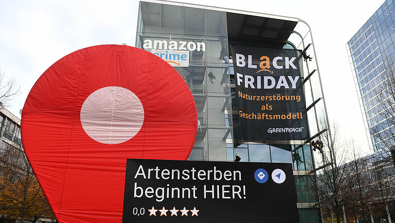 Greenpeace-Aktive protestieren während der Rabattaktion Black Friday gegen die Ressourcenverschwendung des Online-Versandhändlers Amazon am Amazon Deutschland Gebäude und hängen dort Plakate auf mit der Aufschrift "crime" und "Black Friday - Naturzerstörung als Geschäftsmodell".