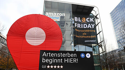 Greenpeace-Aktive protestieren während der Rabattaktion Black Friday gegen die Ressourcenverschwendung des Online-Versandhändlers Amazon am Amazon Deutschland Gebäude und hängen dort Plakate auf mit der Aufschrift "crime" und "Black Friday - Naturzerstörung als Geschäftsmodell".
