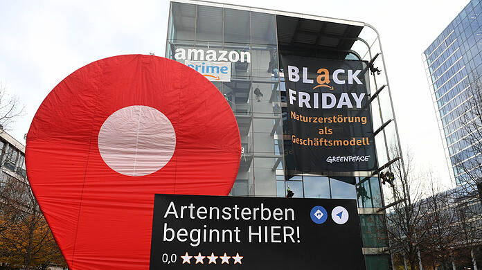 Greenpeace-Aktive protestieren während der Rabattaktion Black Friday gegen die Ressourcenverschwendung des Online-Versandhändlers Amazon am Amazon Deutschland Gebäude und hängen dort Plakate auf mit der Aufschrift "crime" und "Black Friday - Naturzerstörung als Geschäftsmodell".