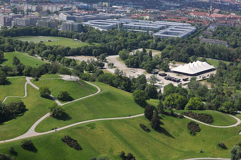 Der Blick nach unten mit Olympiaberg und Tollwood-Festival im Aufbau.