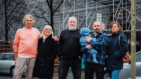 Sie alle wohnen seit über 15 Jahren in dem Gebäudekomplex hinter ihnen. Seit Monaten herrscht hier Großbaustelle. Die Mieterinnen und Mieter versuchen, sich zu wehren: gegen Lärm, gegen Kälte und gegen Bauschutt, der gegen die Fenster knallt.