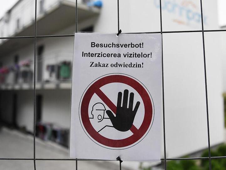 Ein "Besuchsverbot!"-Zettel auf deutsch, rumänisch und polnisch vor dem Betrieb in Mamming. Foto: Angelika Warmuth/dpa/Archivbild