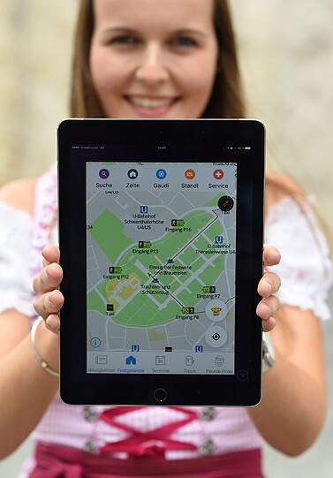 Eine Mitarbeiterin der Stadt München zeigt die neue Wiesn-App mit Geländeplan.