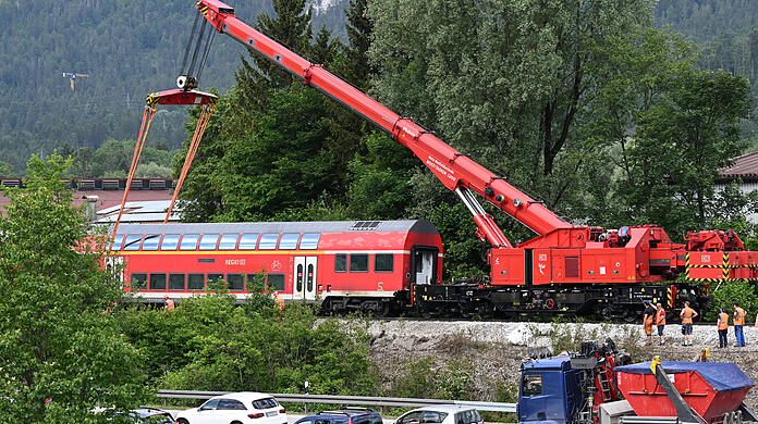 Ein Waggon des verunfallten Regionalzugs hängt für die Bergung an einem Schienenkran.