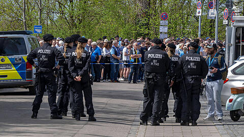 Fußballfans warten hinter der Westkurve des Sechzgerstadions unter den Augen der Polizei auf ihren Einlass.