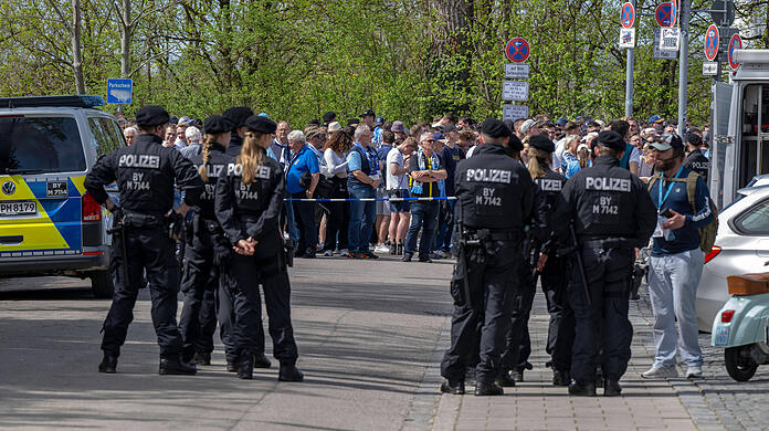 Fußballfans warten hinter der Westkurve des Sechzgerstadions unter den Augen der Polizei auf ihren Einlass.