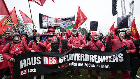 VW-Beschäftigte nehmen an einer Kundgebung der IG Metall vor der Volkswagen-Zentrale teil, während eines Warnstreiks im Stammwerk des deutschen Automobilherstellers in Wolfsburg. Sie verkleiden sich wie die Diebe aus der Netflixserie "Haus des Geldes".