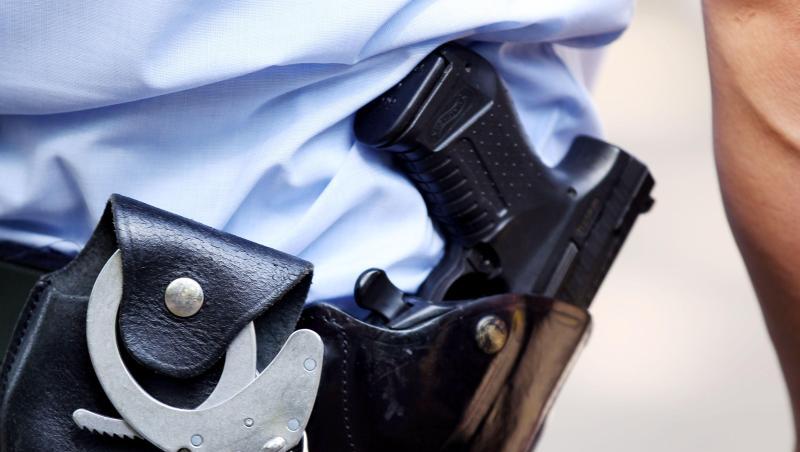 Ein Polizist mit Handschellen und Pistole am Gürtel. Foto: Oliver Berg/dpa/Archivbild