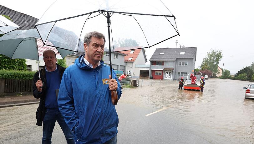 Markus Söder (CSU), bayerischer Ministerpräsident, steht am Rande einer überfluteten Straße vor Journalisten.