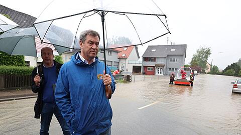 Markus Söder (CSU), bayerischer Ministerpräsident, steht am Rande einer überfluteten Straße vor Journalisten.