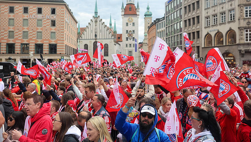Die Fans des FC Bayern  schwenken Fahnen und warten auf den Beginn der Meisterfeier am Marienplatz.