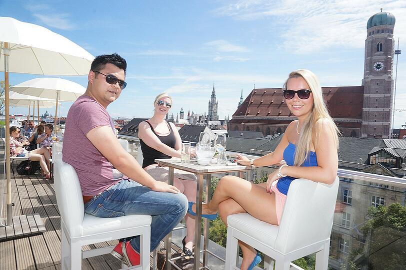 Sie ist bekannt und das mit Recht: Die Dachterrasse des Hotels Bayerischer Hof am Promenadeplatz in der Altstadt. Auf unserem Bild haben es sich die Teamleiterin Andrea (24), die Bankkauffrau Franziska (24) und der IT-Manager Jared gemütlich gemacht. Sie sagen: &bdquo;Es macht Spaß, mitten in der Stadt abzuspannen von der Stadt. Das tut richtig gut!&ldquo;