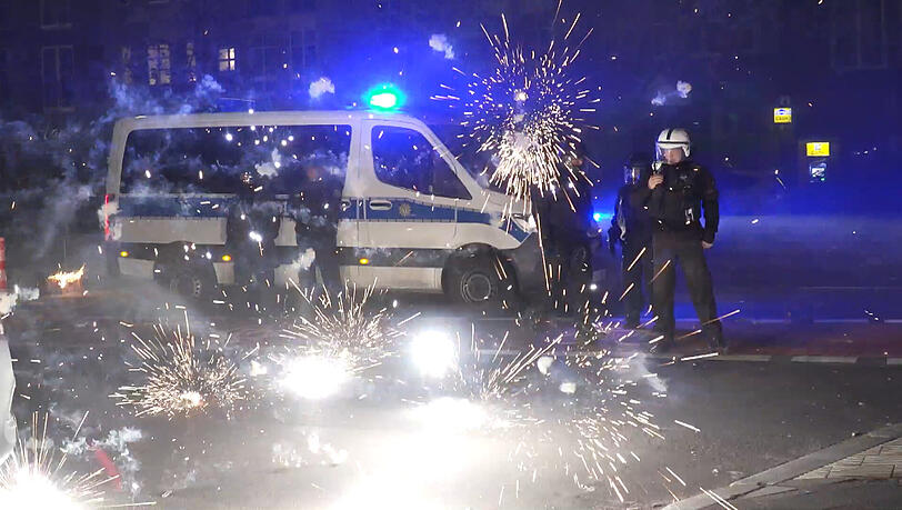 Polizeibeamte stehen hinter explodierendem Feuerwerk. Nach Angriffen auf Einsatzkräfte in der Silvesternacht hat die Diskussion um Konsequenzen begonnen. Berlins Regierende Bürgermeisterin will, dass sich die Innenminister mit dem Thema beschäftigen.
