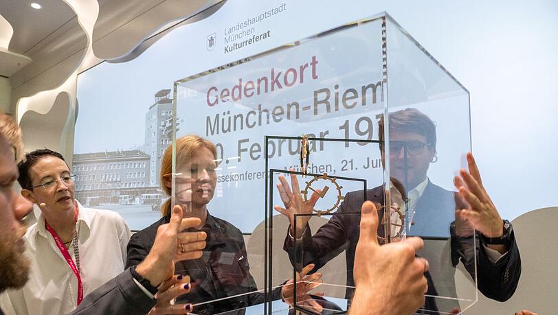 Die Künstlerin Alicja Kwade (M.) nimmt die Glaskuppel vom Modell für den Gedenkort "Riem 1970" ab.