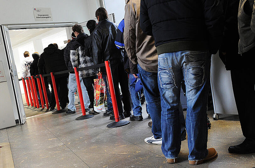 Arbeitslose Menschen stehen in einem Jobcenter Schlange. Die Arbeitslosenzahl in Bayern ist im Januar deutlich angestiegen. (Archivbild)