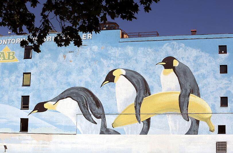 Drei Pinguine tragen eine Banane &ndash; die Seitenwand vom Kontorhaus Brunthaler an der Thalkirchner Straße.
