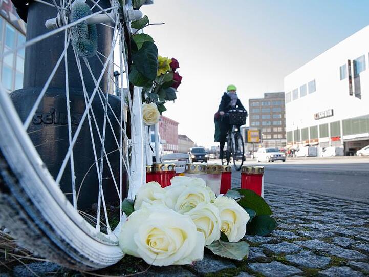 Blumen und Kerzen sind vor einem weißen Geisterrad an der Stelle eines tödlichen Radunfalls in Berlin-Mitte aufgestellt.