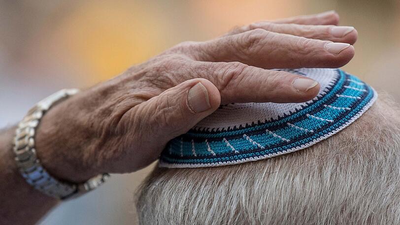 Ein Mann setzt sich auf der Kundgebung zum "Kippa-Tag" auf dem Römerberg seine Kippa auf. (Symbolbild)