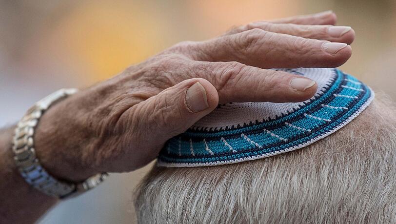 Ein Mann setzt sich auf der Kundgebung zum "Kippa-Tag" auf dem Römerberg seine Kippa auf. (Symbolbild) Ein Mann setzt sich auf der Kundgebung zum "Kippa-Tag" auf dem Römerberg seine Kippa auf. (Symbolbild)