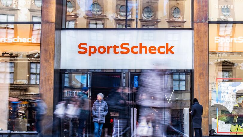 Personen gehen an einer Sportscheck-Filiale in der Münchener Fußgängerzone vorbei.