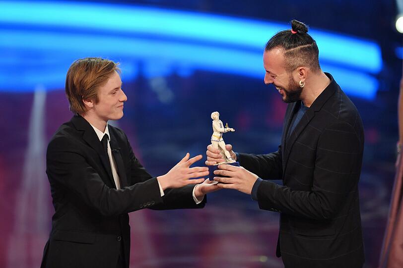 Der Regisseur Jakob M. Erwa (r) erhält vom Schauspieler und Laudator Louis Hofmann seinen Filmpreis. Erwa wurde mit dem Nachwuchsregiepreis für seinen Film "Die Mitte der Welt" ausgestattet