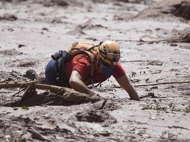 Ein Rettungshelfer arbeitet im Schlamm auf der Suche nach möglichen Opfer des Dammbruchs.