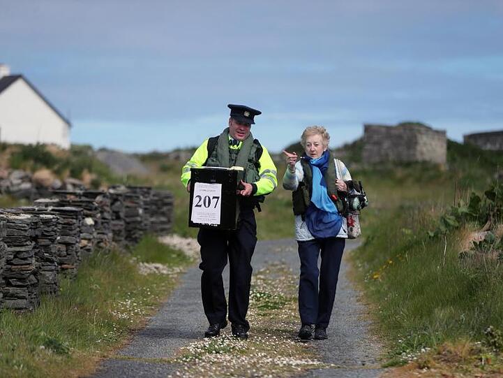 Carmel McBride (r) und Garda Adrian McGettigan tragen eine Wahlurne zu einem Wahllokal auf der Insel Inishbofin. Die Wähler auf der abgelegenen Insel vor der Küste von Donegal gehörten zu den ersten, die bei den Kommunal- und Europawahlen, einen Tag vor dem Rest des Landes, ihre Stimme abgeben.