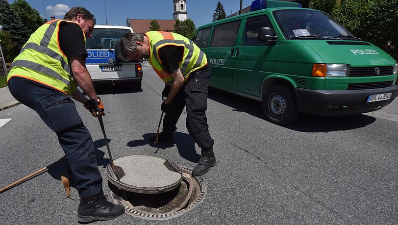 Polizisten arbeiten an einem Gullydeckel (Archivbild). Polizisten arbeiten an einem Gullydeckel (Archivbild).