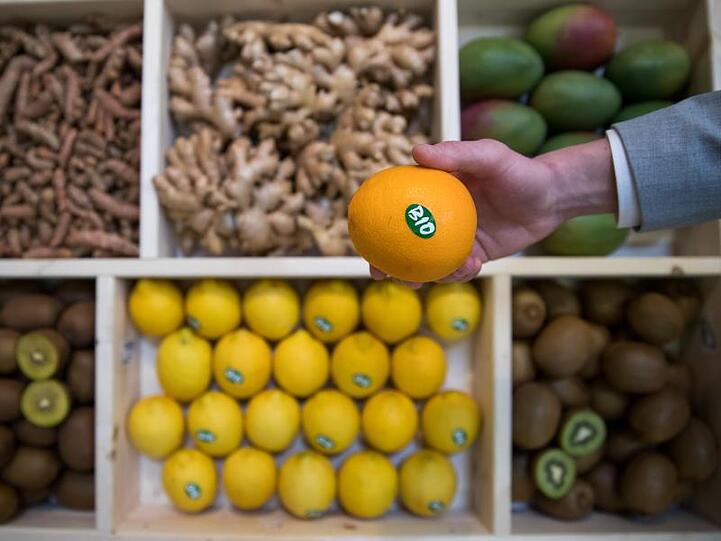 Eine Orange mit Bio-Siegel ist während der Naturkostmesse Biofach an einem Stand zu sehen. Foto: Daniel Karmann/Archiv
