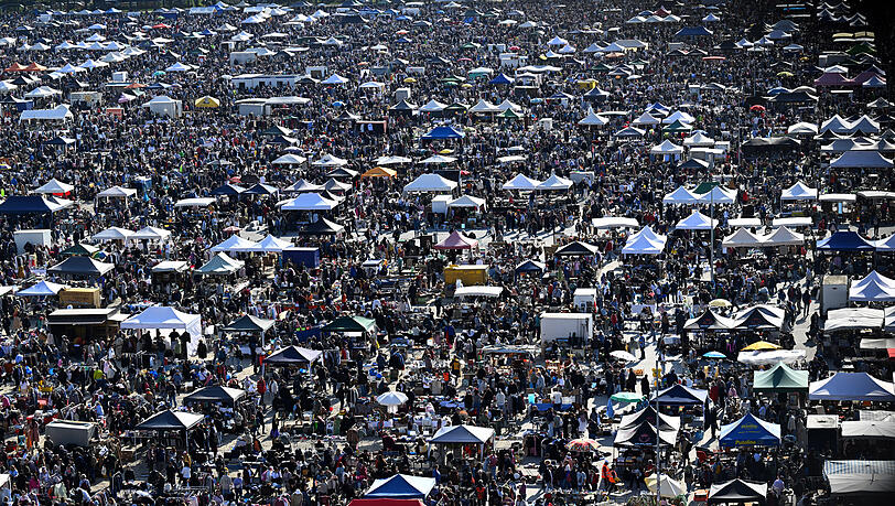 Aus dem Auge der Bavaria-Statue sind Besucher des Flohmarkt des Deutschen Roten Kreuzes (DRK) auf der Theresienwiese zu sehen.
