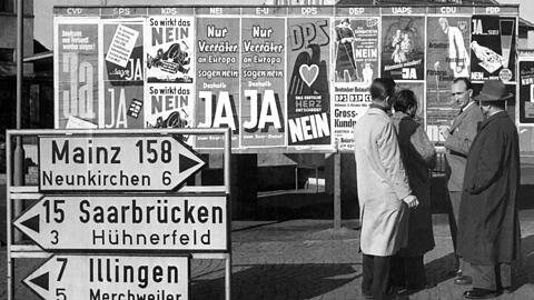 Rege Diskussionen führen Passanten am 20. Oktober 1955 in Beckingen (Saarland) vor einer Anschlagtafel, auf der alle zugelassenen Parteien ihr Für und Wider das zwischen Paris und Bonn vereinbarte "Europäische Saarstatut" propagieren (Archivfoto). Bei der Volksabstimmung am 23.10.1955 entschied sich die Bevölkerung des Saarlandes gegen das Saarstatut und damit für die Rückkehr des Grenzlandes zur Bundesrepublik.