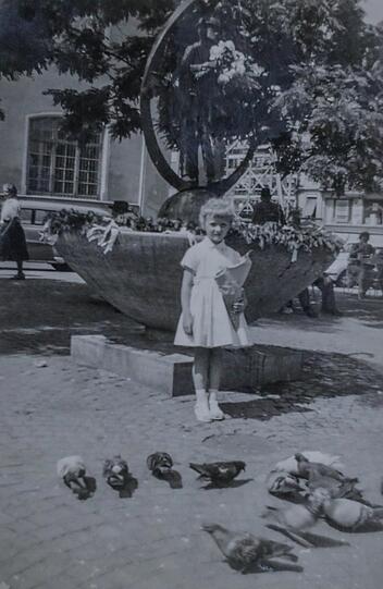Inge Rainer 1957 mit der Schultüte und Tauben vor dem Valentinsbrunnen, ihre Oma hat damals ihre Blumen-Verkaufskiste genau gegenüber.