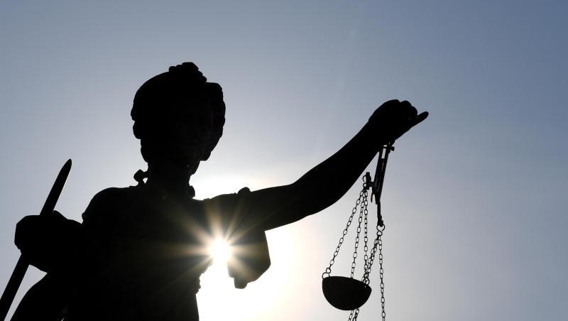 Eine Statue der Justitia mit einer Waage und einem Schwert in ihren Händen.