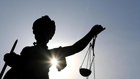 Eine Statue der Justitia mit einer Waage und einem Schwert in ihren Händen.
