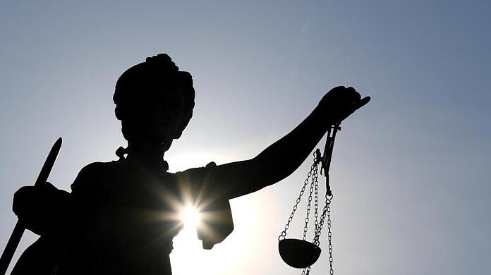 Eine Statue der Justitia mit einer Waage und einem Schwert in ihren Händen.