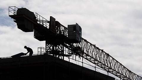 Ein Arbeiter arbeitet auf dem Dach eines Rohbaus in einem neuen Wohnquartier in Hannover.