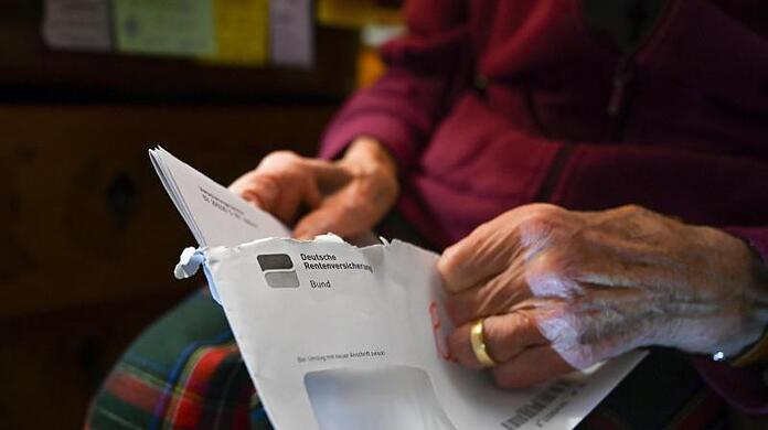 Eine Seniorin hält ihren Rentenbescheid in der Hand.